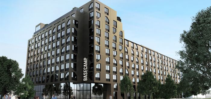 Illustration av ett flerbostadshus med mörk fasad och texten ”BASECAMP” på byggnaden.