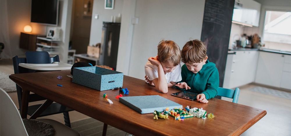 Två pojkar sitter vid ett bord och spelar på en ipad