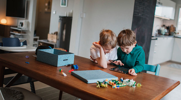 Två pojkar sitter vid ett bord och spelar på en ipad